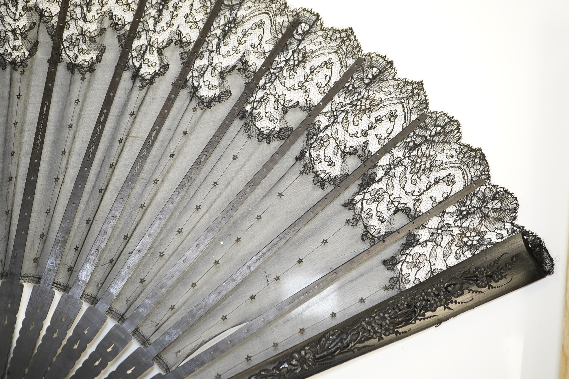 An Edwardian evening fan with black silk gauze, decorated sequin and lace trimmed leaf with carved ebonised guards and stems, in a fan box by J. D’uvelleroy. Condition - fair to good